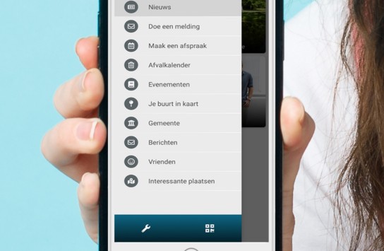 Hand houdt smartphone vast met menu van Kortenberg-app, opties zoals nieuws, meldingen en afspraken zichtbaar. (vergroot foto)